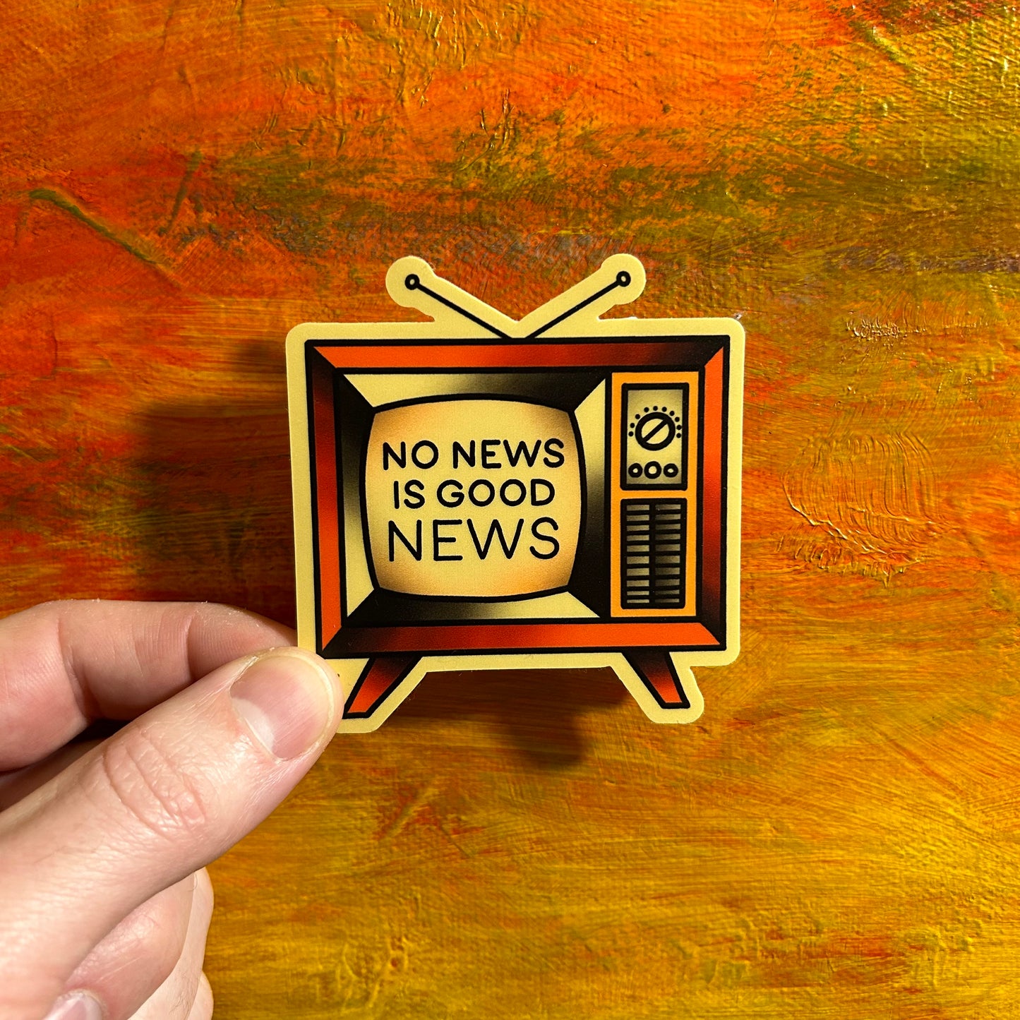 Off white die cut illustrative retro sticker of an old TV and on the screen it’s says “no news is good news”.