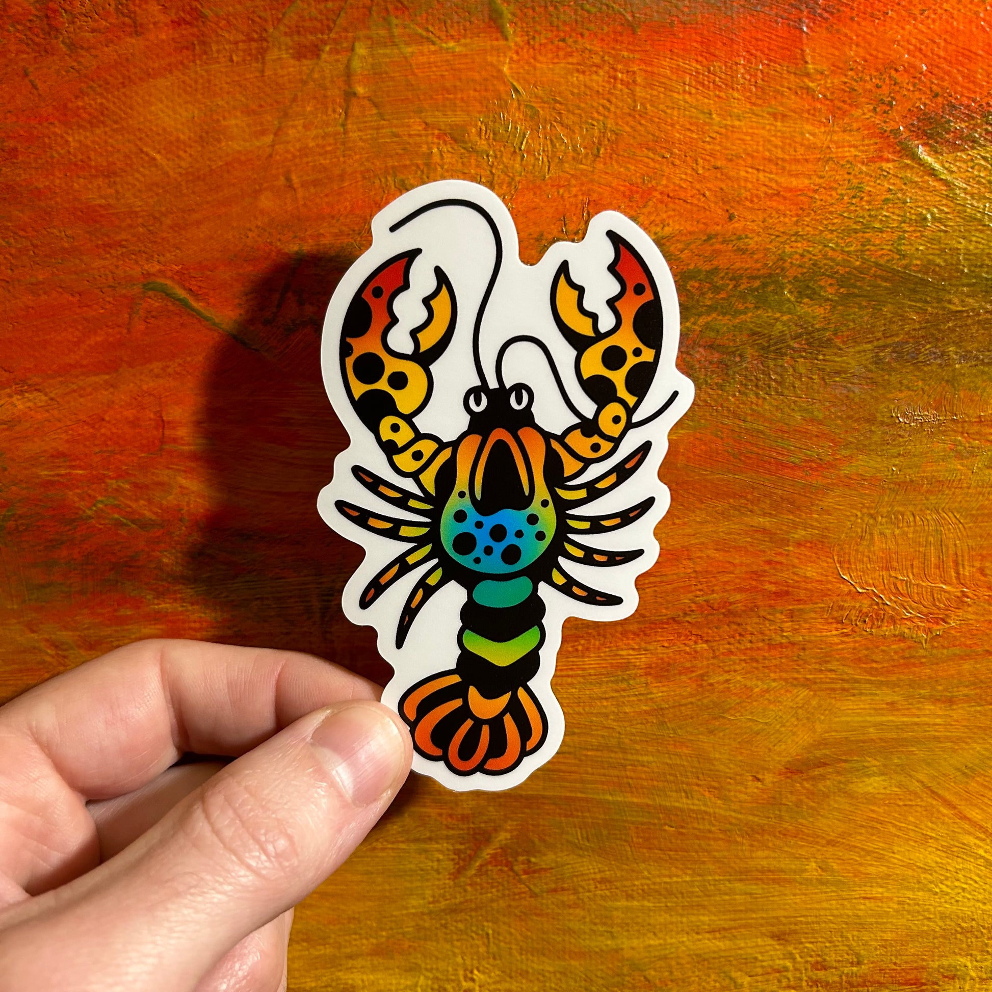 Illustrative sticker of a lobster with bold black lines and red yellow blue and green in the body.