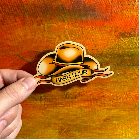 Tan die cut illustrative sticker of a Stetson cowboy hat and underneath on a banner it says “barn sour”.