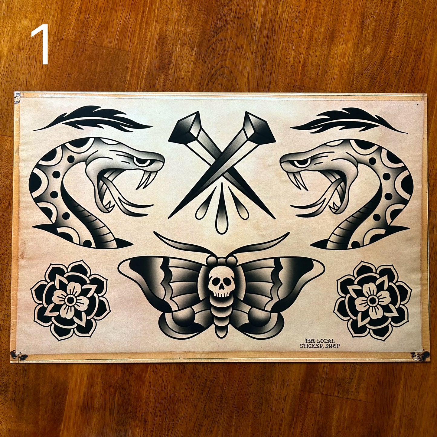 Art print of tattoo flash. Snakeheads looking at each other, set of nails between them, a death moth below and 2 black flowers next to it. A decorative piece of art for wall, shop, workshop, home, work.