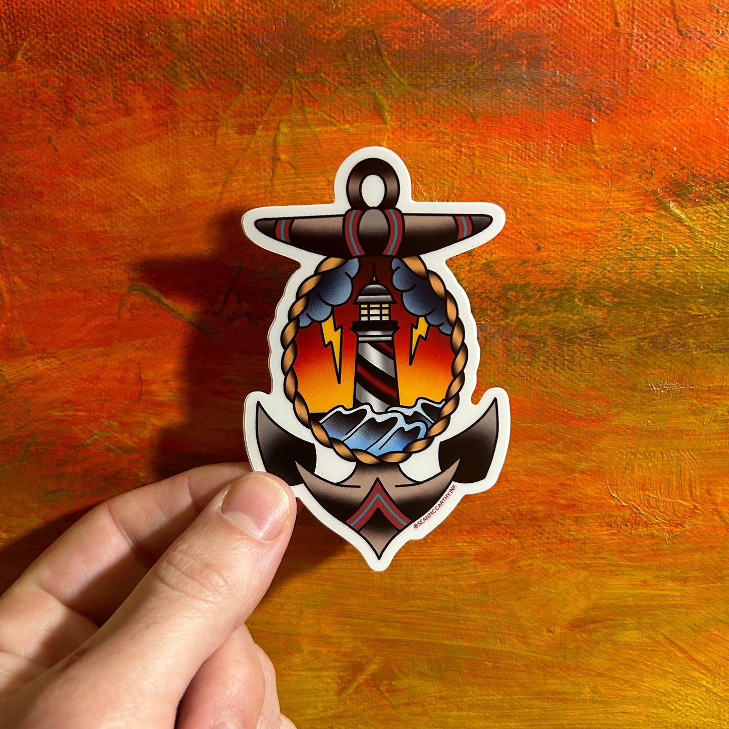 A colourful sticker of an anchor. In the middle of the anchor, framed by a rope, is a dark ocean scene with lightning, sunset and rolling waves. Tattoo style.