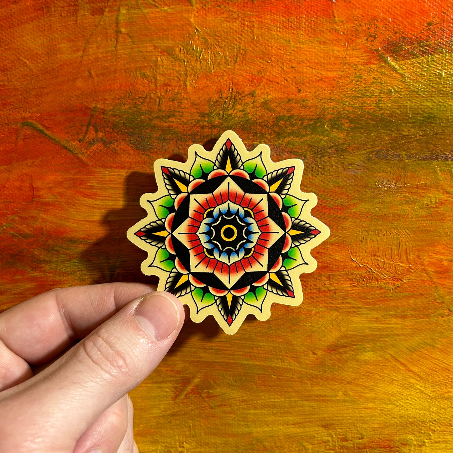 Black Flower mandala with an off white background. Some of the petals are coloured symmetrically in red, yellow and green. Beautiful illustration of an abstract mandala.