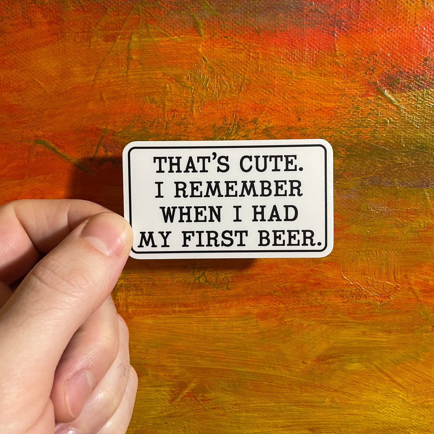 A sticker of a quote from the movie, Step Brothers. A white rectangle with black typewriter type font saying “that’s cute. I remember when I had my first beer.”