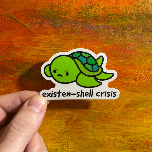 Cute kawaii sticker of an illustrative angry green turtle cartoon and underneath it says “existen-shell crisis”.